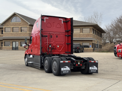 Conventional sleeper truck tractor rear three-quarter view showing Freightliner Cascadia 126 with red cab and black chassis in a lot.