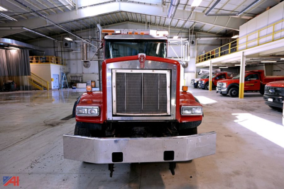 Kenworth T8 Series dump truck front view in a showroom with large grille and metal bumper.