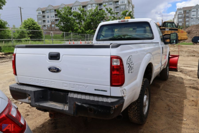 Ford F-250 Super Duty pickup truck rear view in a construction lot, white, used, with tailgate and bumper, 4x4 badge on side, cargo bed visible.