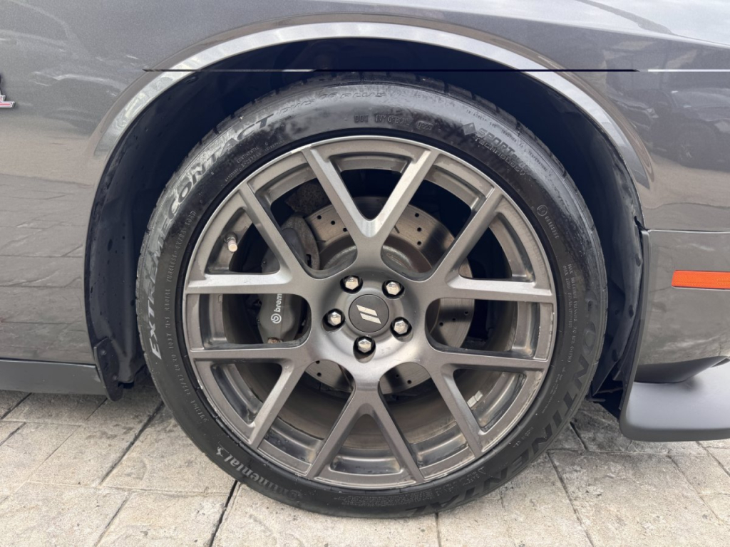 Wheel and tire close-up on a 2018 Dodge Challenger showing a multi-spoke alloy rim and high-performance brake rotor