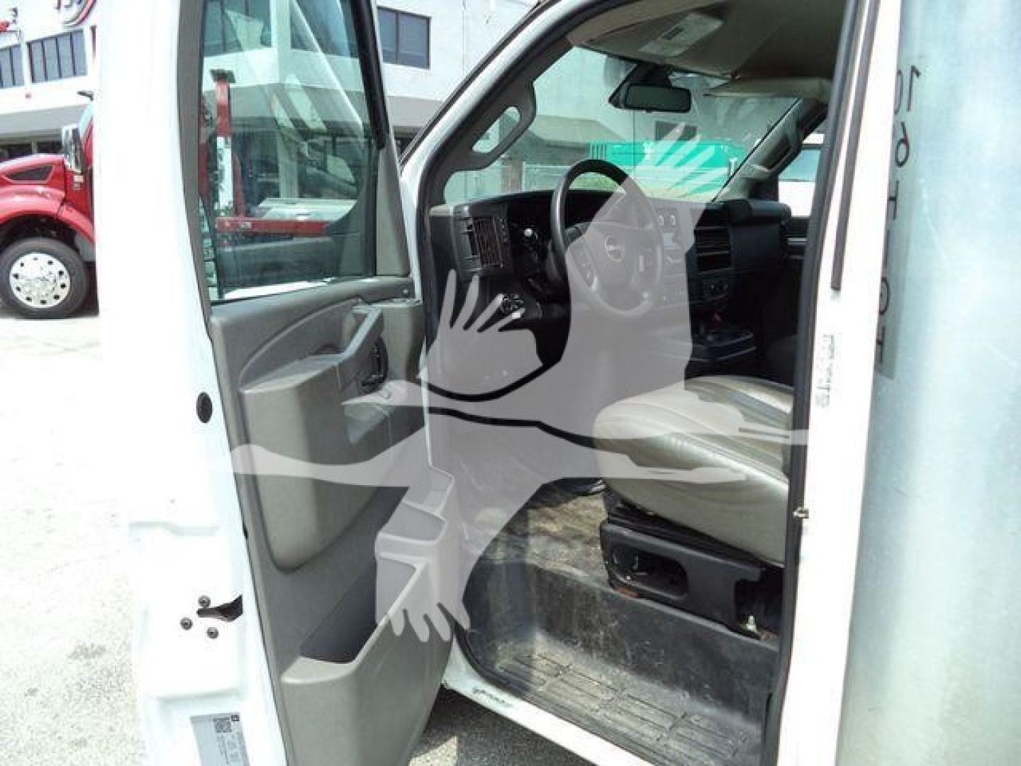 Interior cabin of a white GMC G3500 cutaway truck with driver's door open, showing floor mat and steering wheel, dashboard, and front seat.