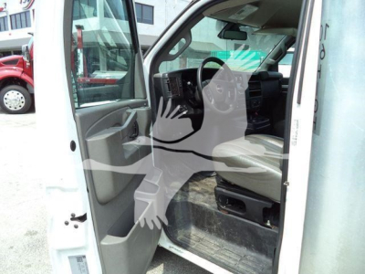 Interior cabin of a white GMC G3500 cutaway truck with driver's door open, showing floor mat and steering wheel, dashboard, and front seat.