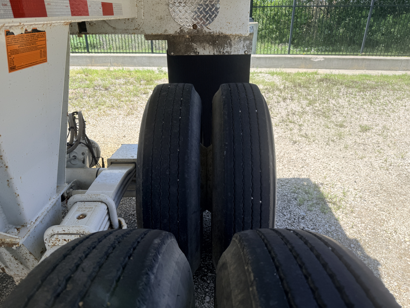 Trailer axle group with dual rear axles and tires visible, part of a dump trailer chassis.