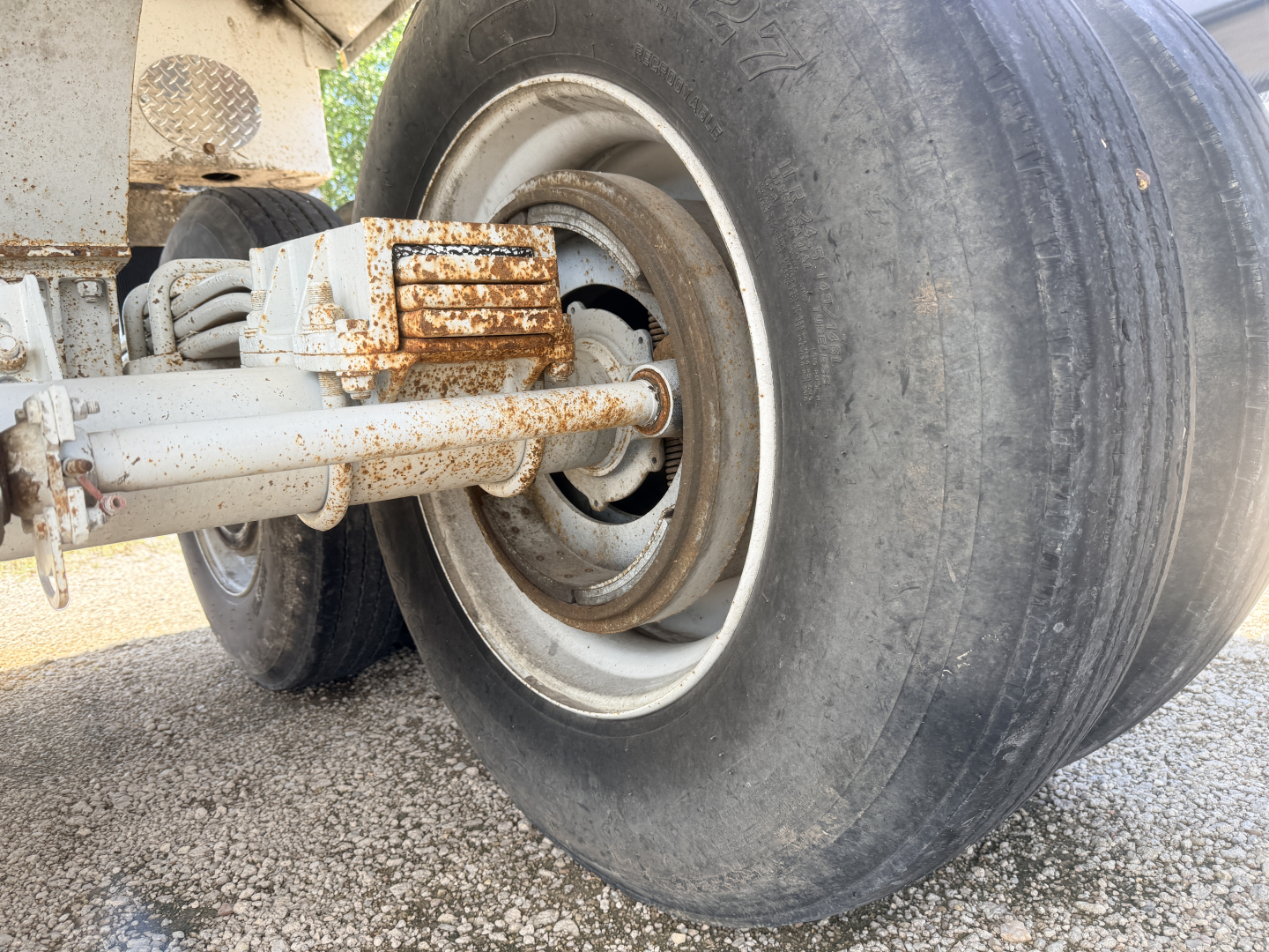 Truck trailer wheel with suspension and rusted components visible.