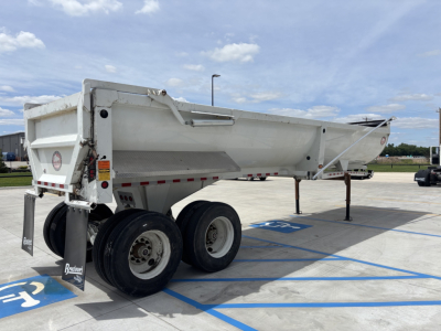 Dump trailer with dual rear axles and raised sidewall showing B2983L stock number plate and accessibility markings.