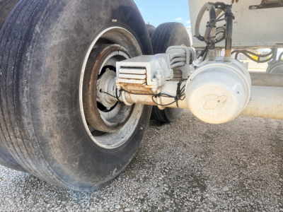 Trailer axle with dual tires and differential/axle housing showing mechanical components and rust-free metal surfaces.