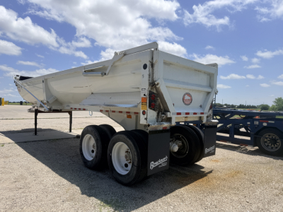Dump trailer showing dual rear axles with white hopper, BLAINCORP Branded mudflaps and tires; side reflection and VIN plate visible.