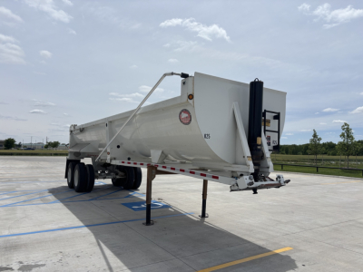 Dump trailer with gooseneck hitch and white body in parking lot showing trailer legs and rear hydraulic system.