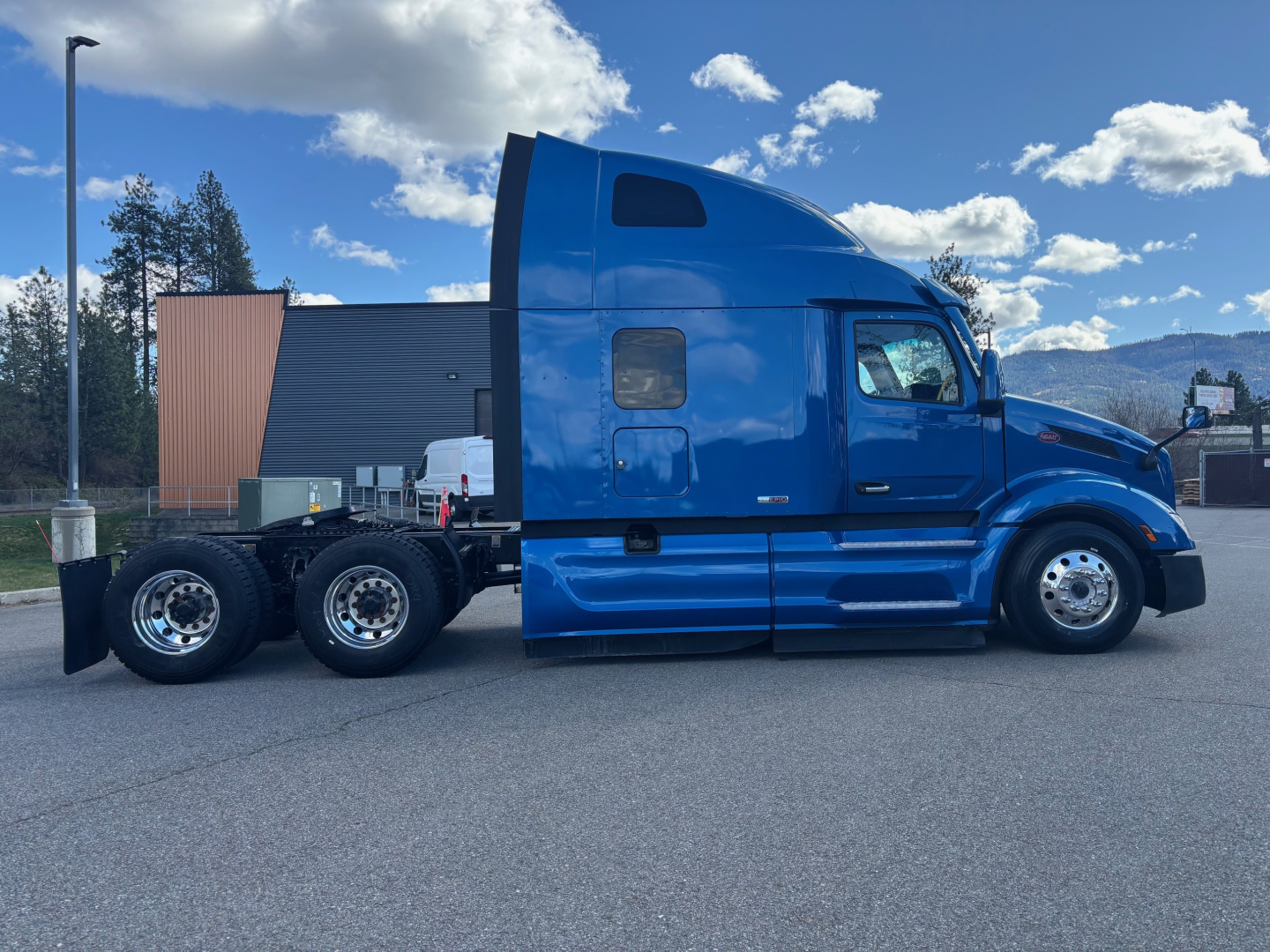 Blue 2022 Peterbilt 579 conventional sleeper semi-truck side view, showing cab, sleeper, chassis, and dual rear axles.