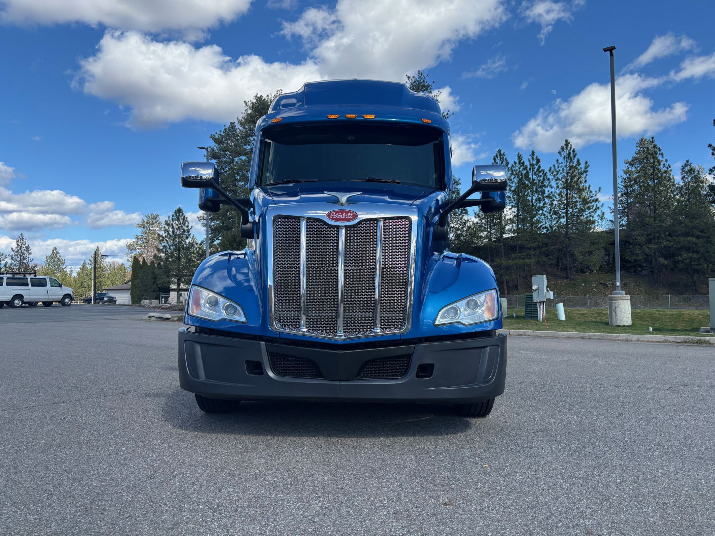 Peterbilt 579 truck front view in blue with chrome grille and black bumper, daytime outdoor lot.