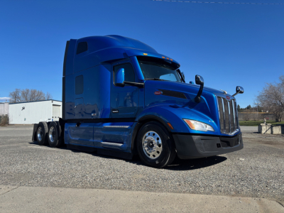 Peterbilt 579 tractor in blue, side view showing sleeper cab and dual rear axles with chrome wheels.