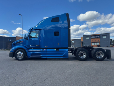Peterbilt 579 tractor side view with blue cab and sleeper, showing truck frame and rear axles.