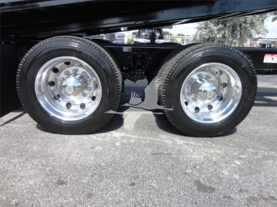 Two rear wheels of a Kenworth W900 chassis with polished rims, dual rear axles visible, undercarriage and suspension components in view.
