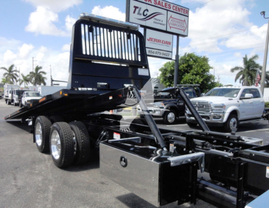 Kenworth W900 rollback truck chassis with heavy-duty frame and dual rear wheels, front view shows hydraulic lines and back of cab structure.