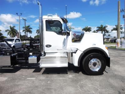 Kenworth W900 truck side view showing chrome exhaust stack and white cab, with platform and fuel tanks visible.