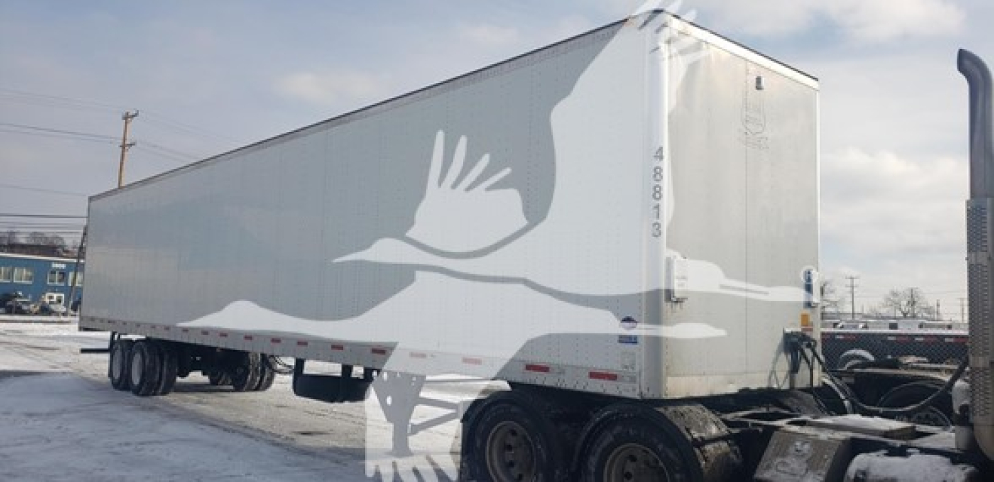 Utility 4000D-X trailer showing side profile of bird graphic and white exterior with wheel axles