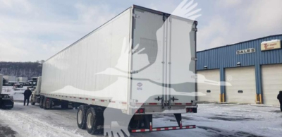 Trailer back and side view showing a 2019 Utility 4000D-X van trailer with dual rear doors and bumper; snow on ground, dealership building in background.