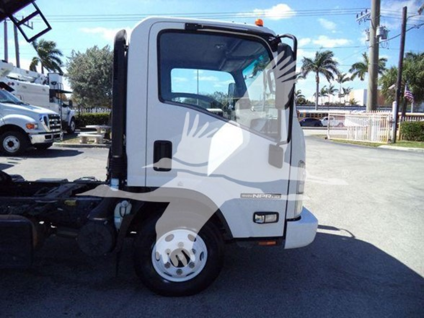 Isuzu NPR cab view showing front wheel and door, with model badge and windows visible.