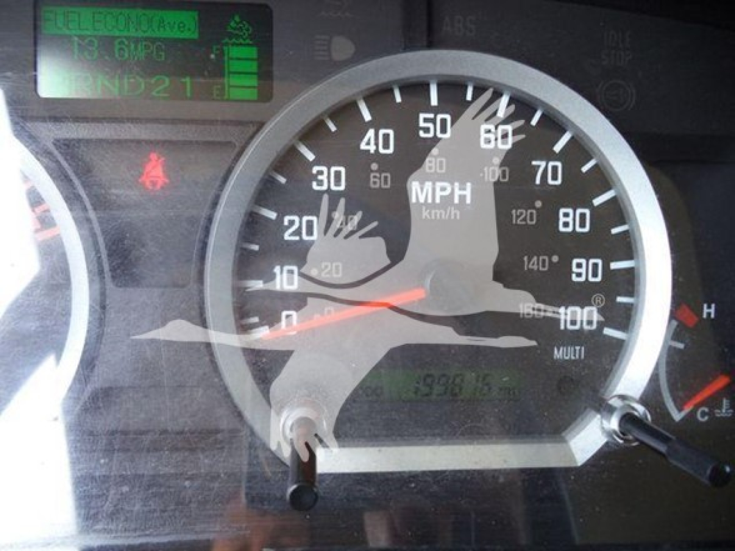 Isuzu NPR dash cluster showing speedometer up to 100 mph, odometer area, and digital display; visible text includes '13 GPC' and 'NPR' reflections; warning icons present.