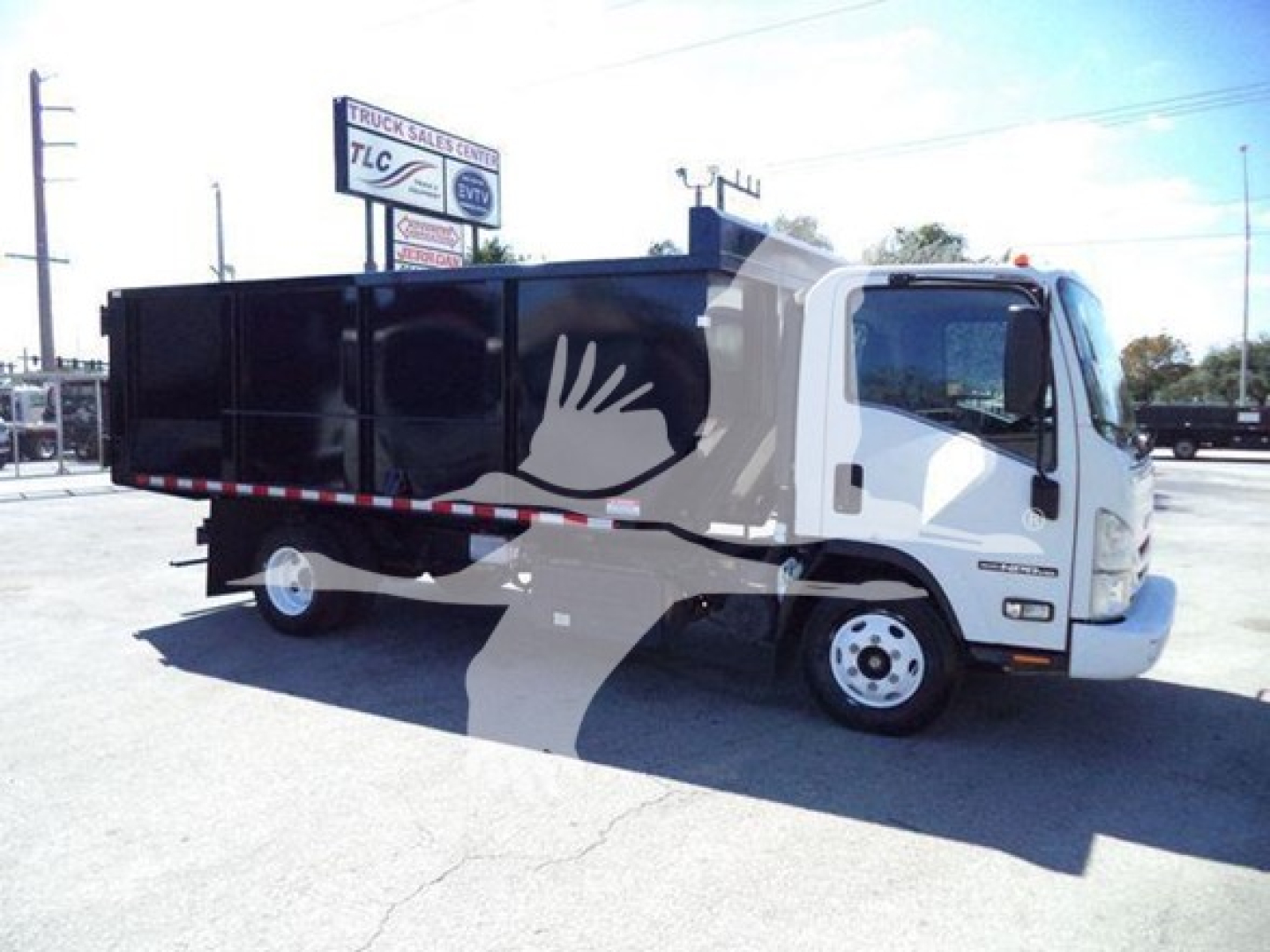 Isuzu NPR dump truck in service showing cargo bed and side profile with white cab and black dump body.