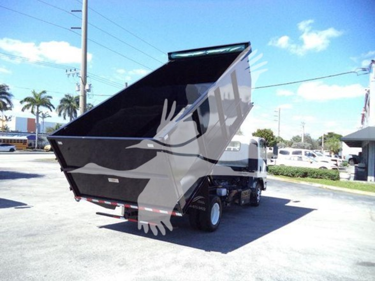 Isuzu NPR dump truck with raised dump bed viewed from rear-right side showing cargo bed and chassis.