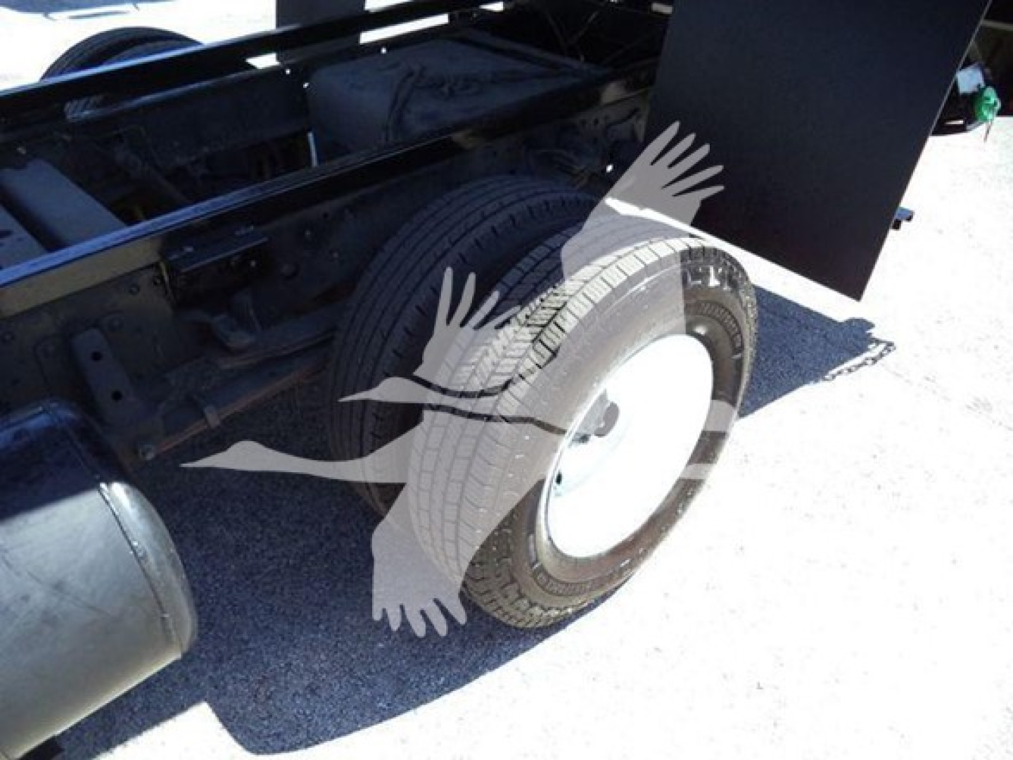 Isuzu NPR dump truck wheel well and chassis with tire visible, no legible text visible on components.