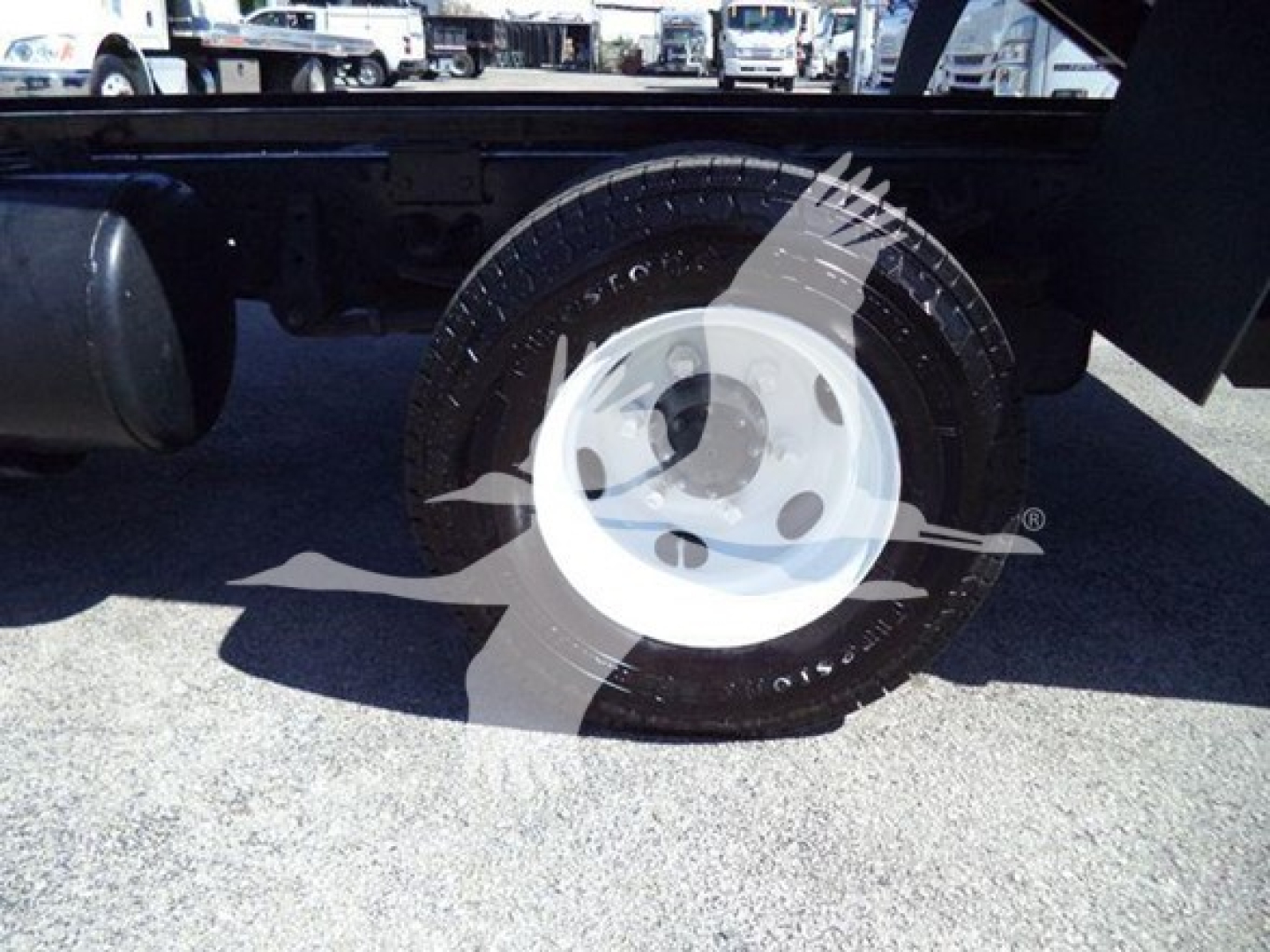 Isuzu NPR wheel and tire view showing white steel wheel and tire with surrounding undercarriage components.