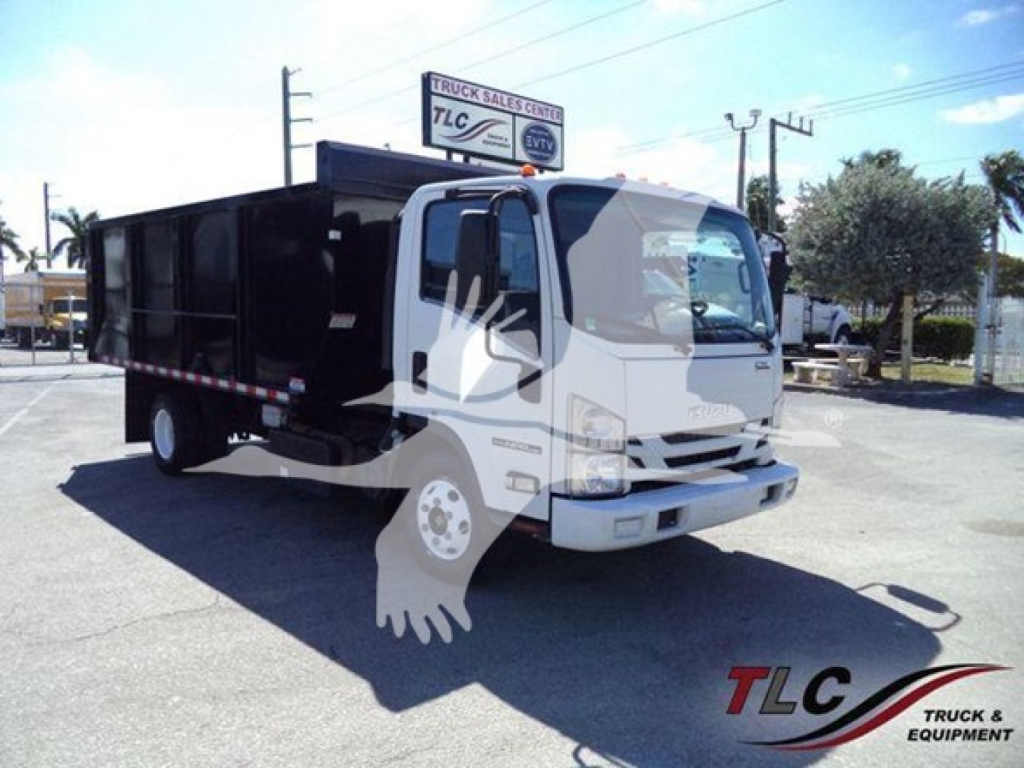 Isuzu NPR dump truck in-service showing cab and black dump body with TLC truck sales center sign in background.