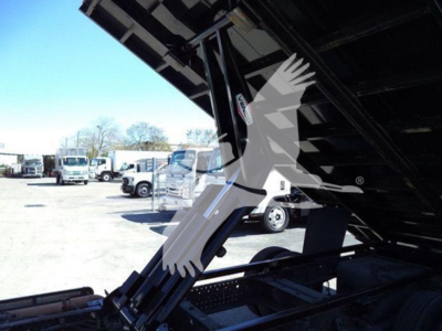 Isuzu NPR dump truck showing hydraulic lift under-bed and surrounding lot of trucks.