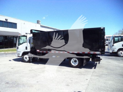 Isuzu NPR dump truck side view showing black dump body and cab, with white front fender and wheel wells, in a lot.