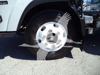 Front wheel of Isuzu NPR dump truck showing white steel wheel and tire with wheel cover removing clearance.
