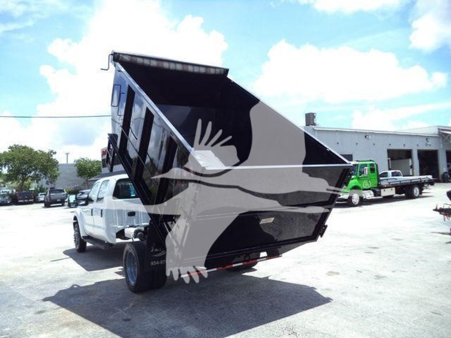 Dump truck bed on a Ford F-550 dump truck raised at a lot with other trucks in background.