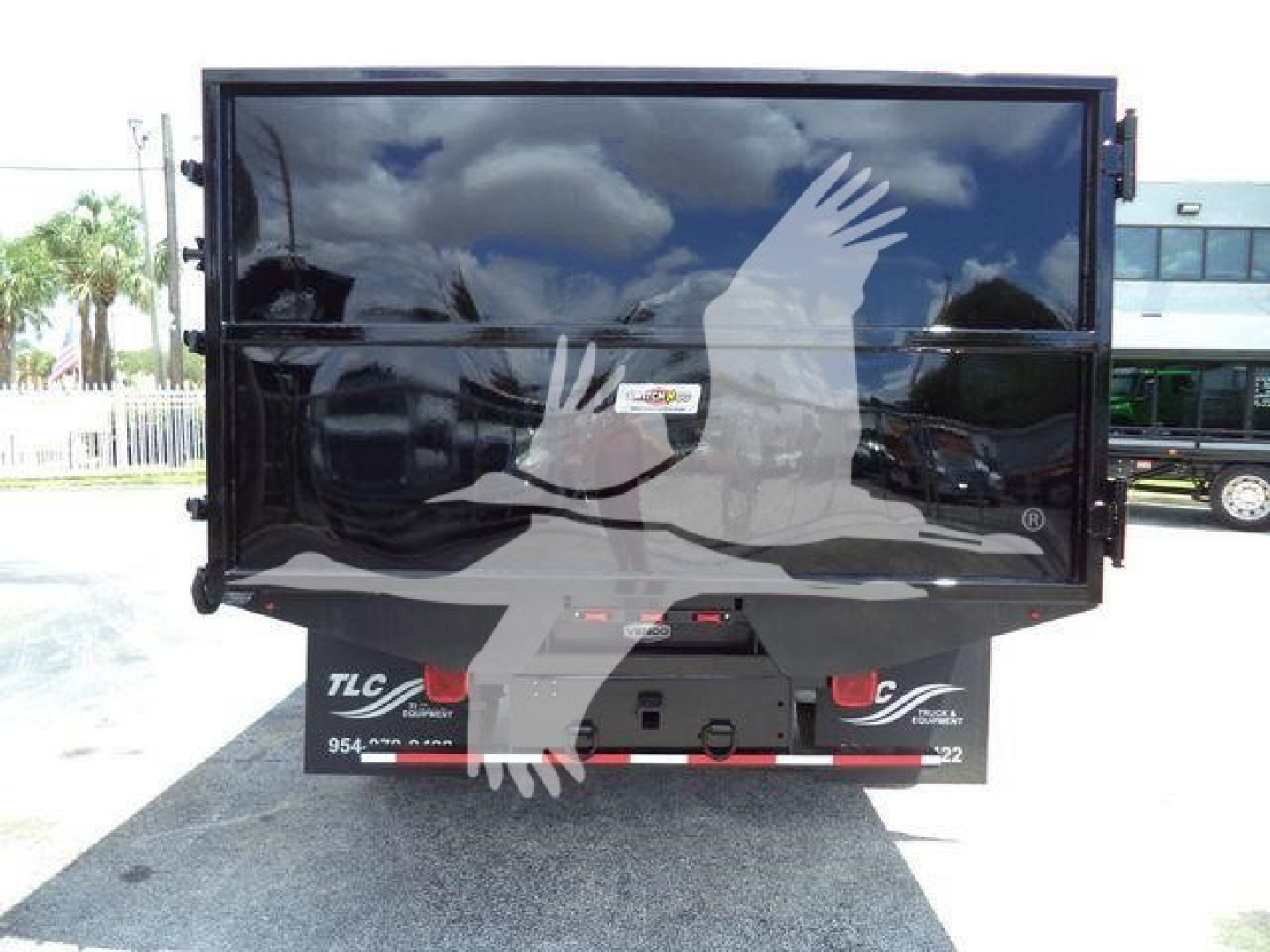 Truck dump bed or tailgate of a Ford F-550 dump truck seen from rear; black bed with reflective surface and rear bumper area