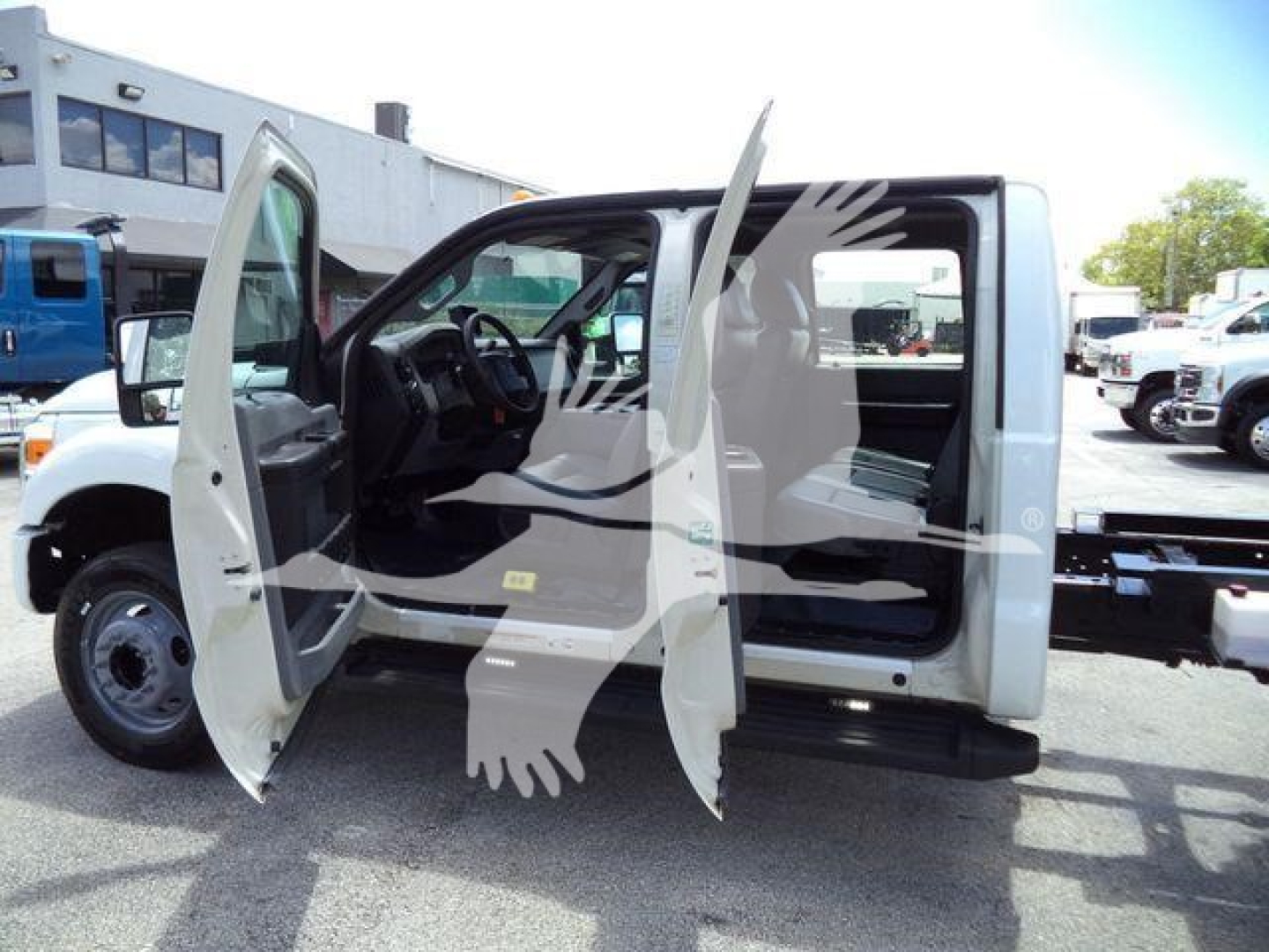 2016 Ford F550 with front and rear doors open showing interior; cab area visible with steering wheel and seats; background shows dealership lot with other trucks.