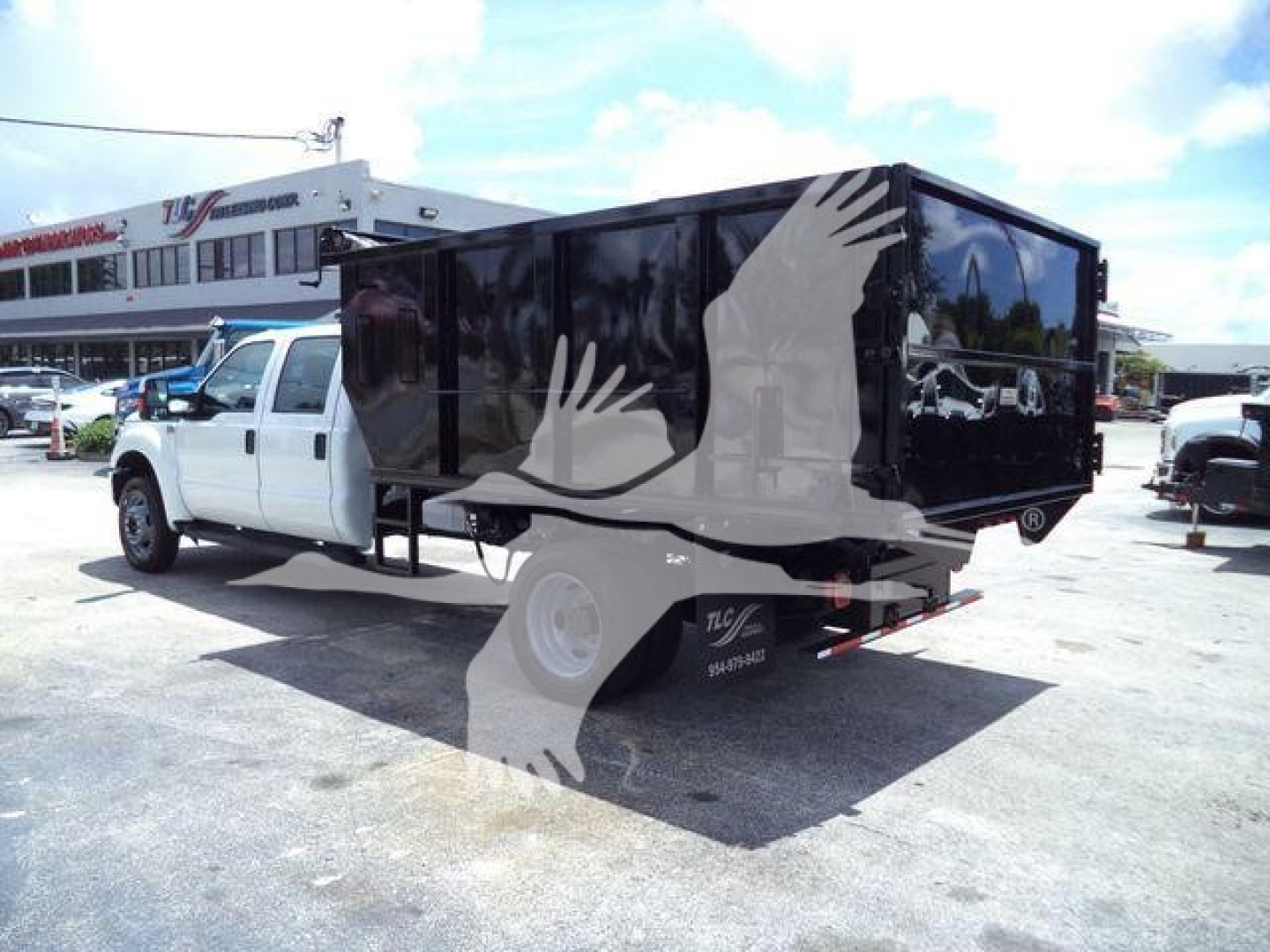 Ford F-550 dump truck with a black enclosed dump bed in a showroom lot.