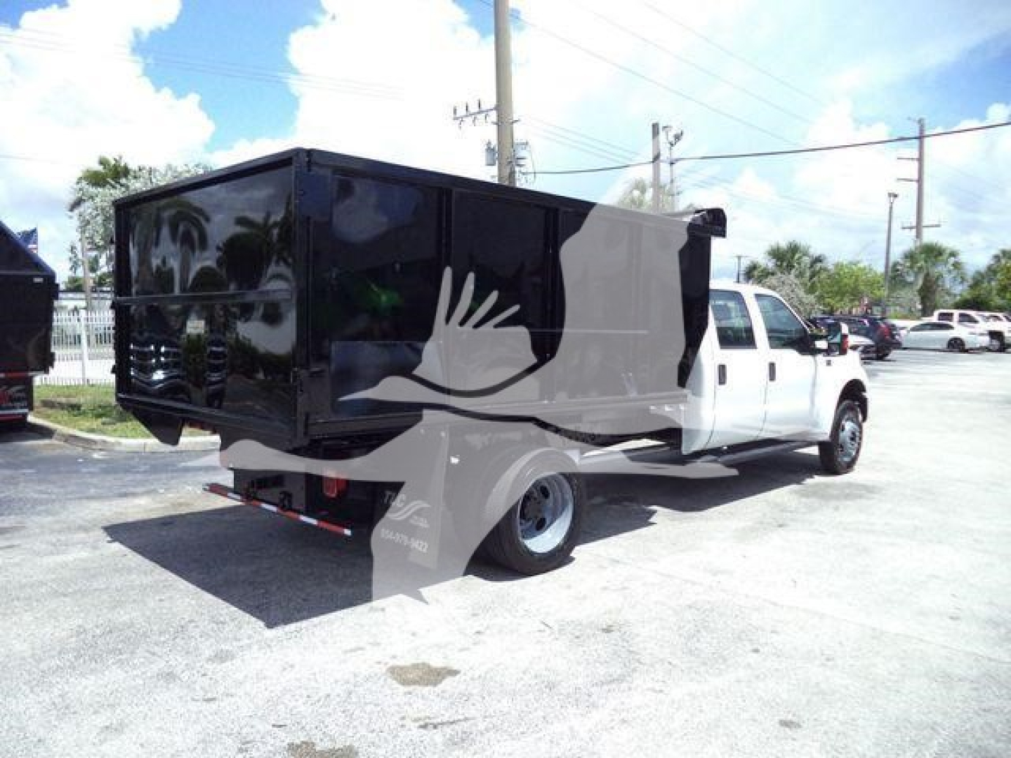 Ford F-550 dump truck with a black utility box mounted on a white cab, rear view showing dump box and dual rear wheels.