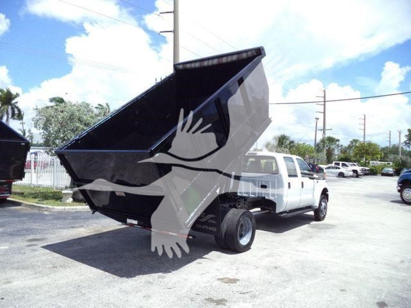 Truck with raised dump bed on a white Ford F-550 dumpside showing dual rear wheels and open hopper.