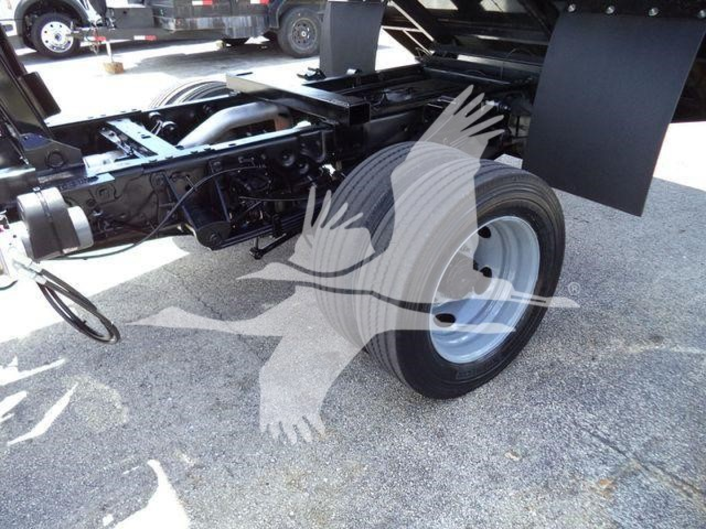 Ford F-550 cabless chassis with single rear axle; wheel and undercarriage visible; part of a dump truck chassis.