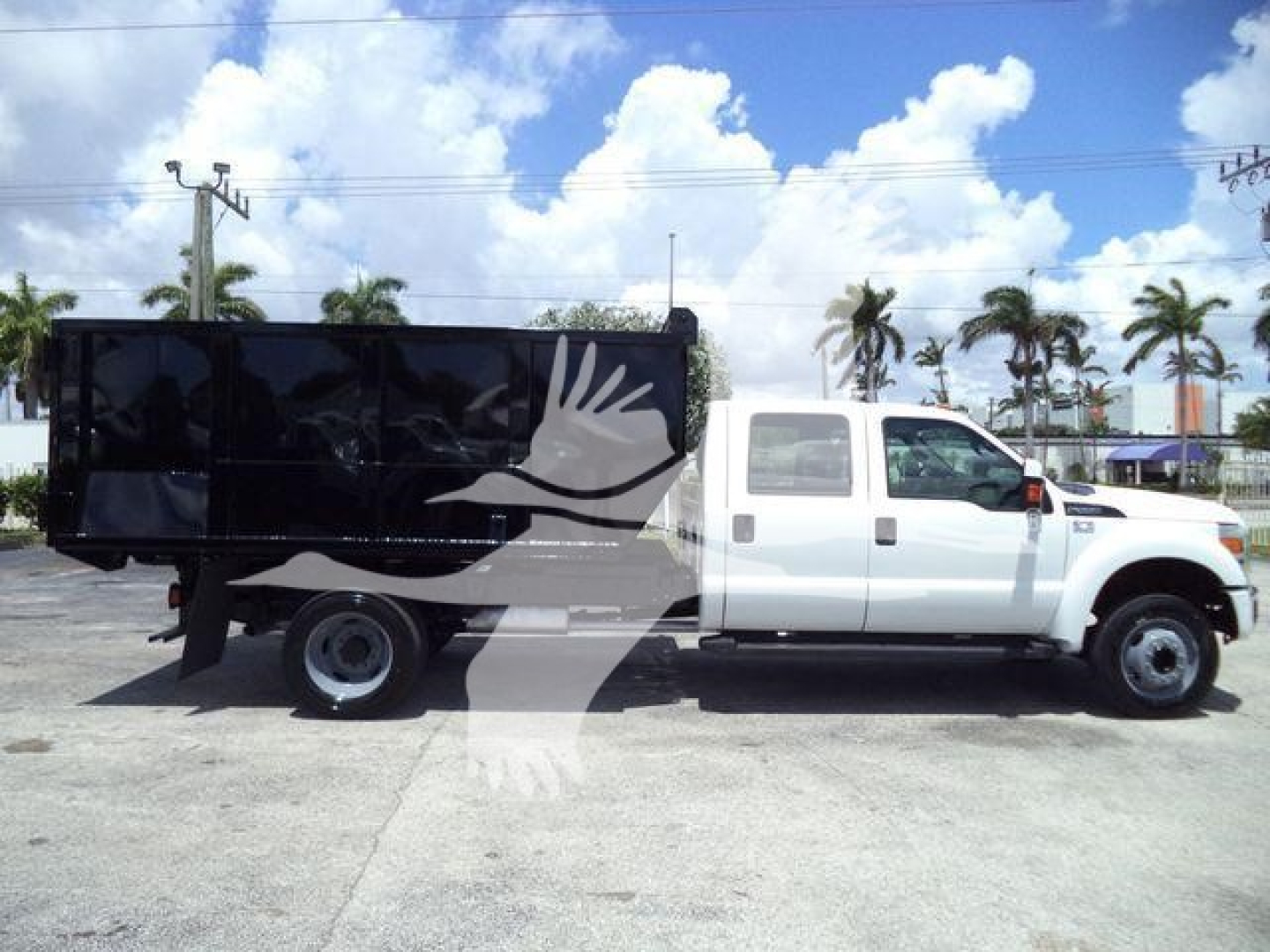 Ford F-550 dump truck side profile with white cab and black dump bed under a blue sky.