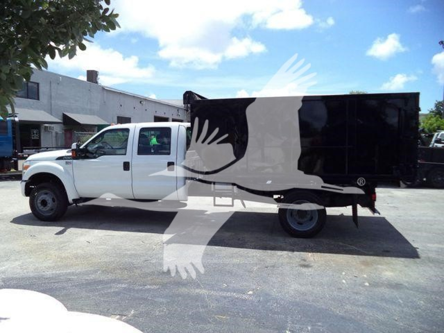 Ford F-550 dump truck side view, white cab with black dump body, under bright blue sky with few clouds.