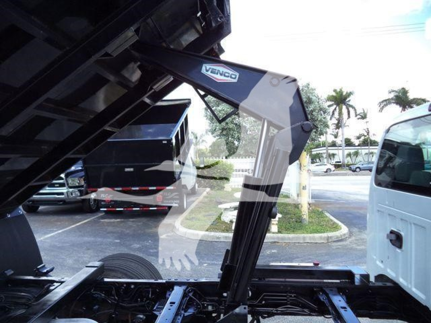 Truck bed with hydraulic arm labeled Venco and black metal frame visible inside truck chassis.