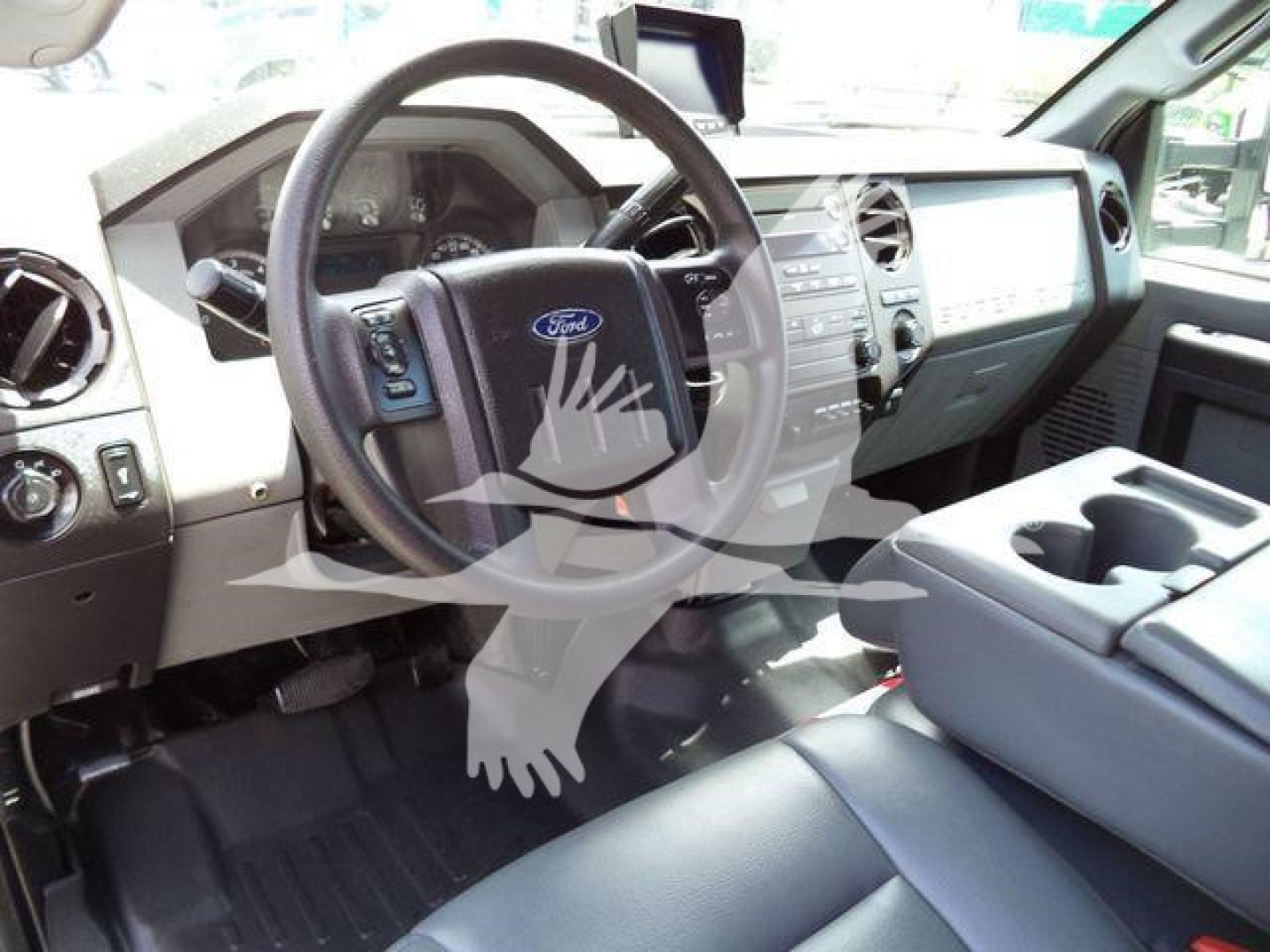 Ford F-550 interior showing steering wheel with Ford emblem, dashboard, and center console; visible are cupholders and front seats.