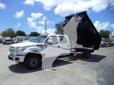 2016 Ford F550 dump truck with a raised black dumpster bed showing a front grille and side mirrors; clear sky with scattered clouds.