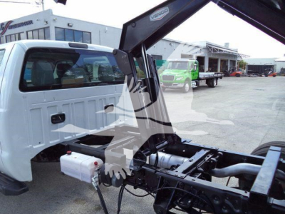 Ford F-550 dump truck chassis with hydraulic crane arm and fuel/fluids tanks visible.