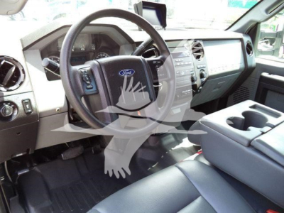 Ford F-550 interior showing steering wheel with Ford emblem, dashboard, and center console; visible are cupholders and front seats.