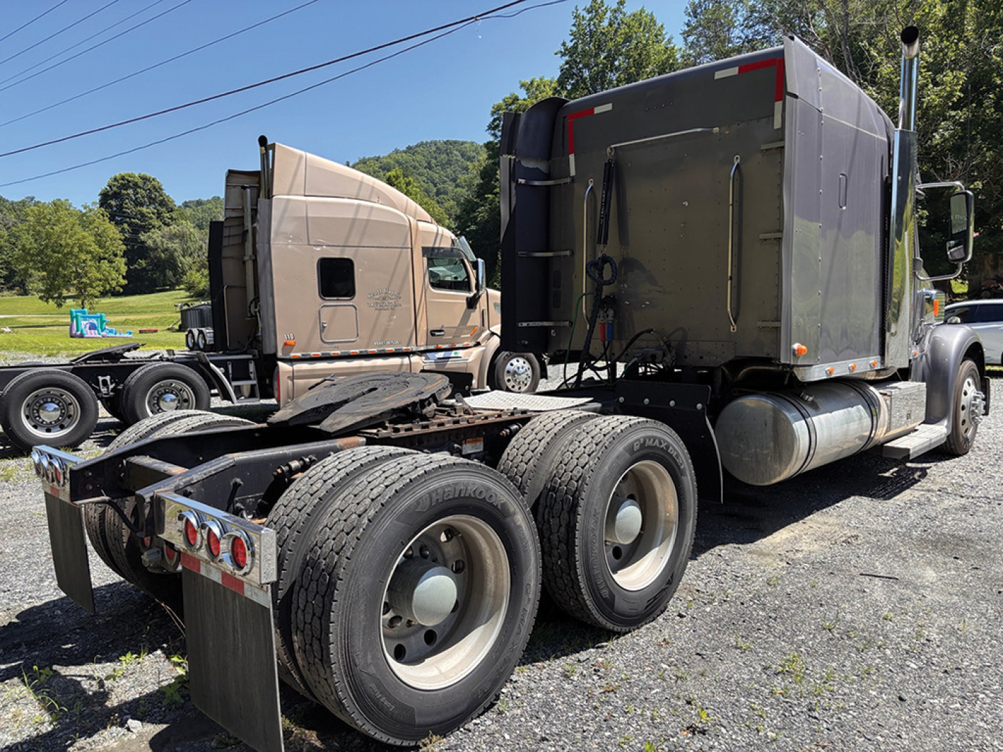 Side and rear view of a Freightliner Coronado semi-truck tractor with dual rear axles and sleeper, showing tires, exhaust, and cab.