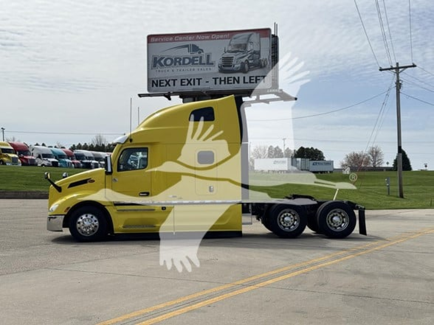 Peterbilt 579 conventional sleeper tractor in yellow with banner a white overlay graphic on side, side view showing sleeper cab and chrome wheels.