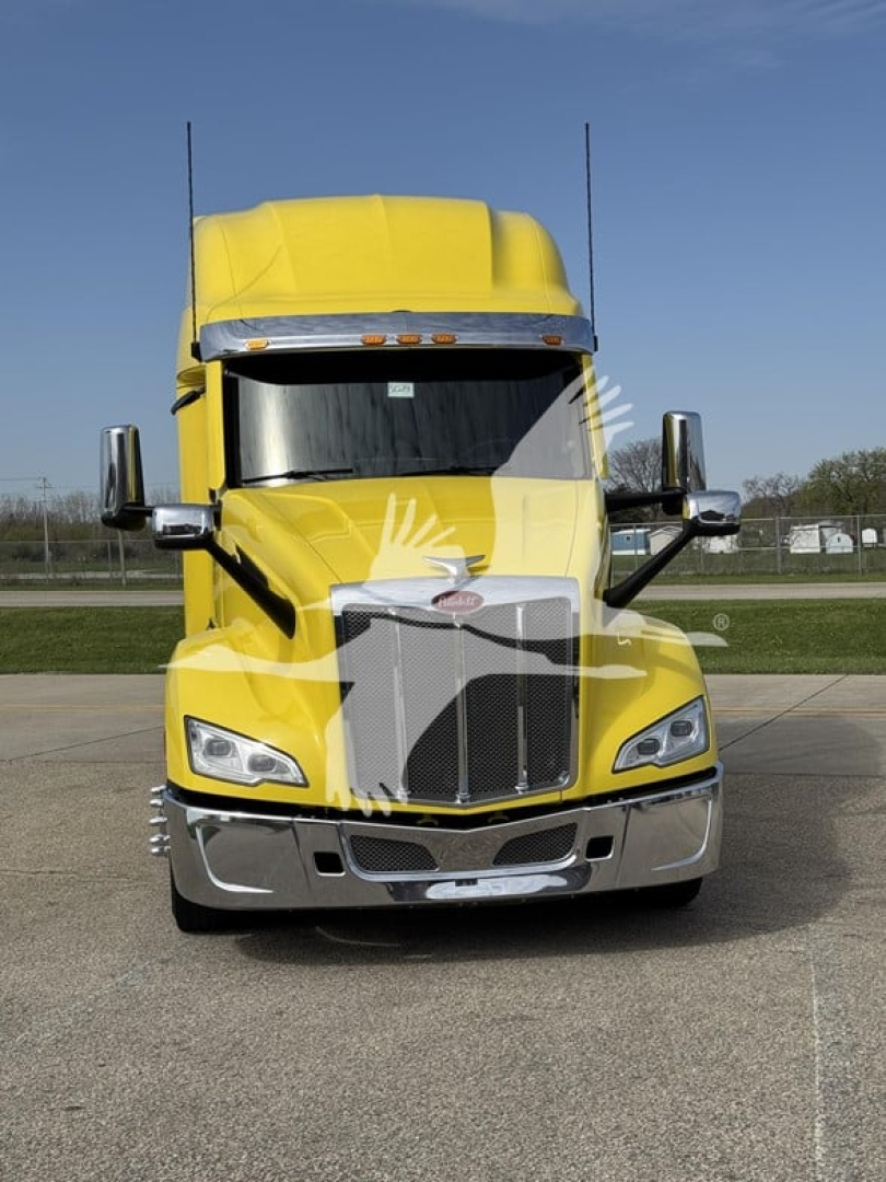 Peterbilt 579 semi-truck front view in yellow, with large chrome grille, twin exhaust stacks, and side mirrors.
