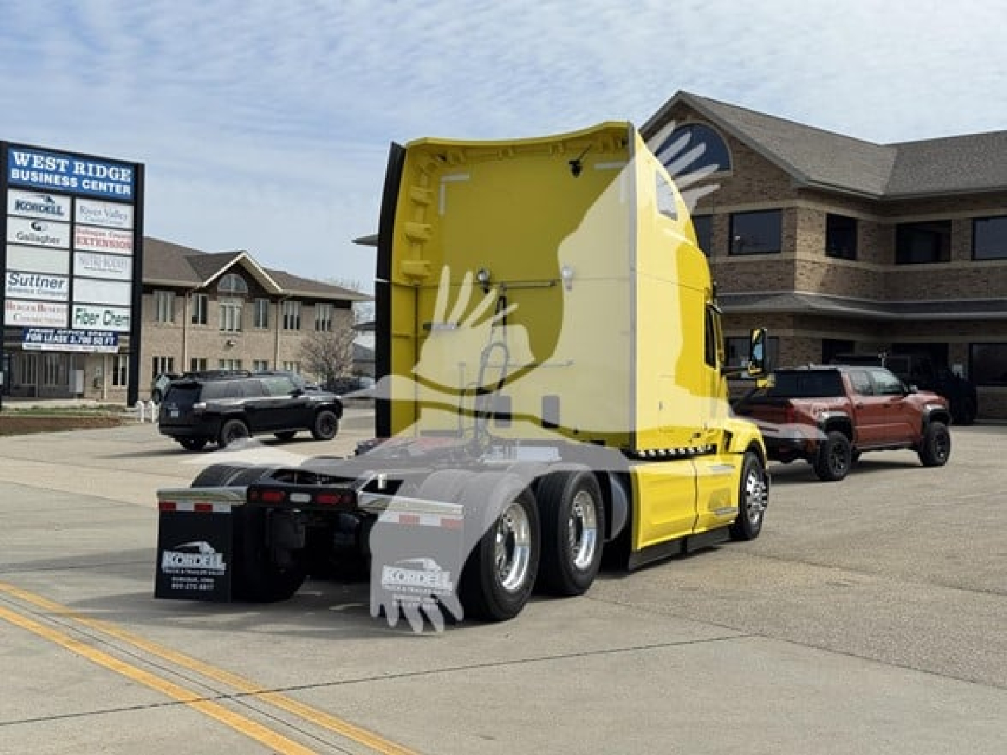 Peterbilt 579 side rear view showing yellow sleeper cab and grey dual rear axles in a dealership lot.