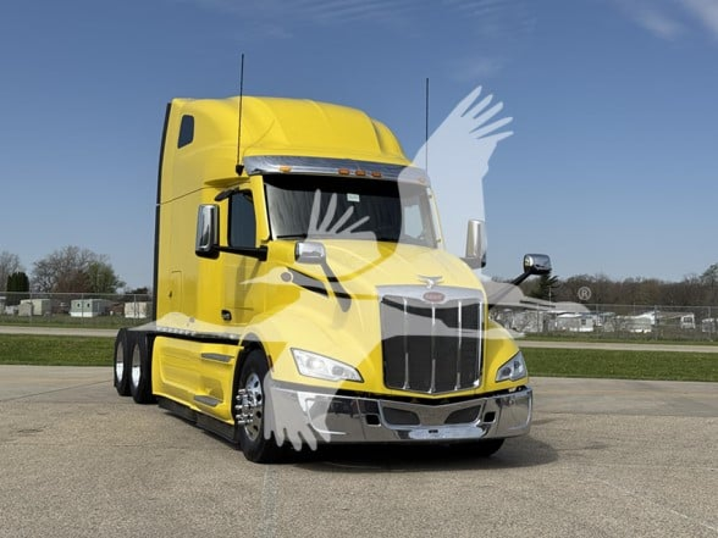 Peterbilt 579 conventional sleeper truck in yellow, front view showing chrome grille, headlights, and side mirrors.
